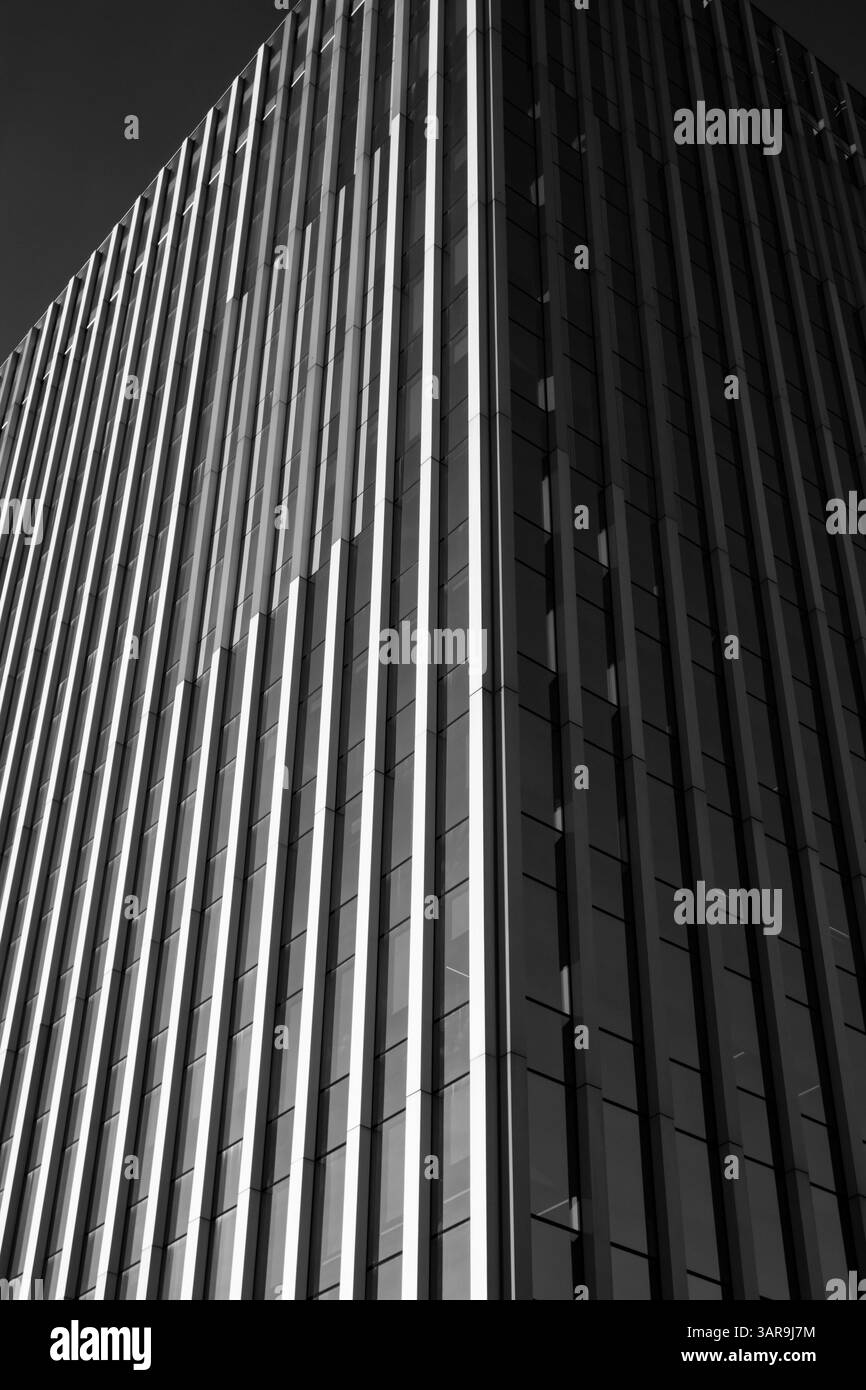 An impressive modern skyscraper reaches into a clear blue sky, showcasing architectural prowess and design. The building has sleek lines. Urban scene. Stock Photo