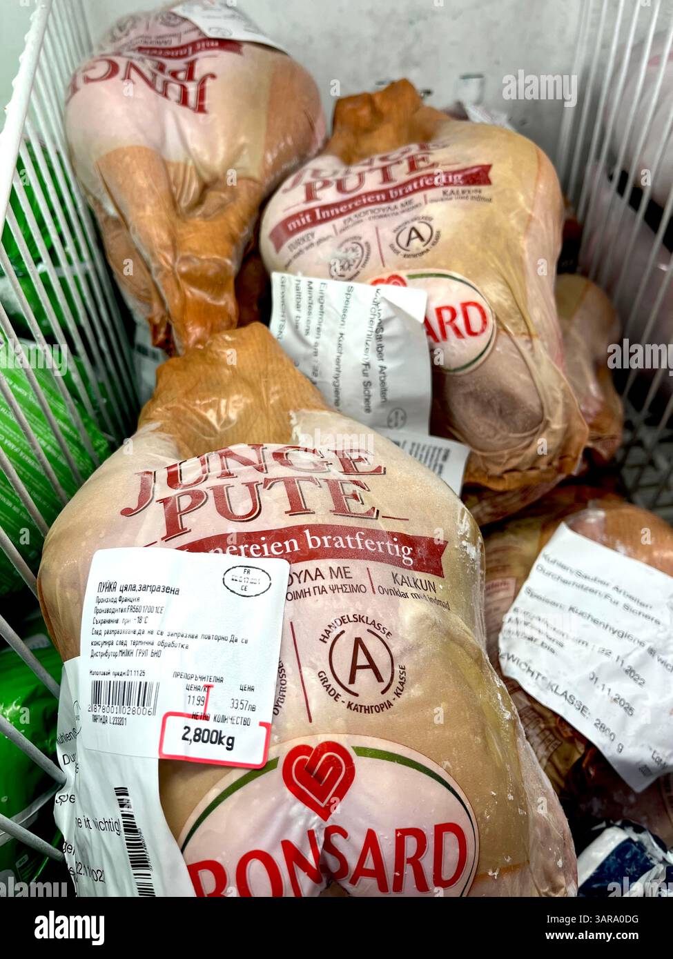 Whole young turkey labeled 'Junge Pute' displayed in a supermarket freezer, prepared for retail sale as a frozen poultry product. - Smartphone Captured Stock Image