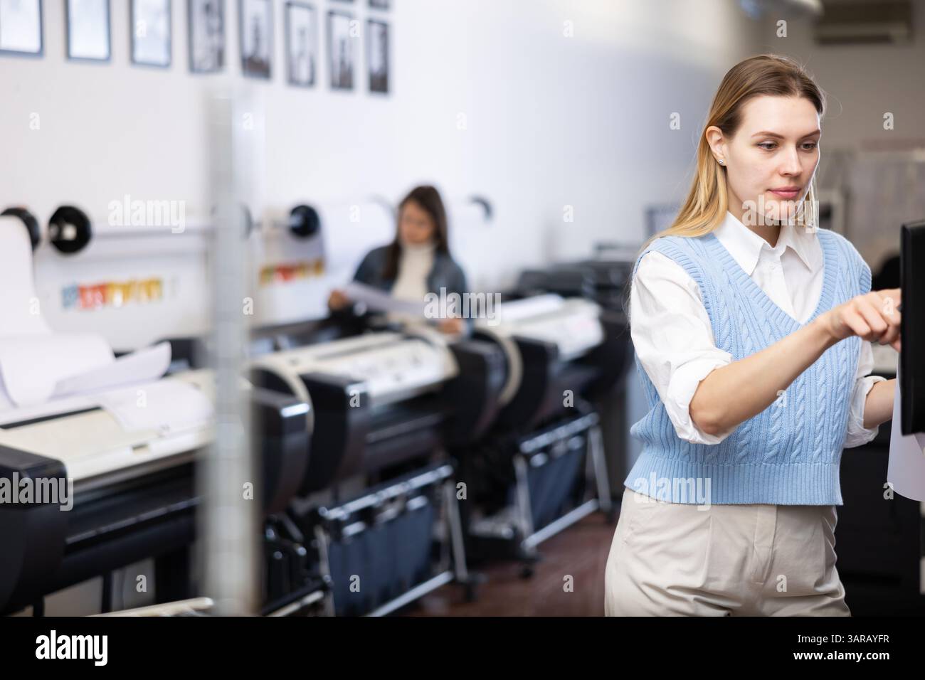Technician operator calibrating plotter machine, typing on computer keyboard Stock Photo