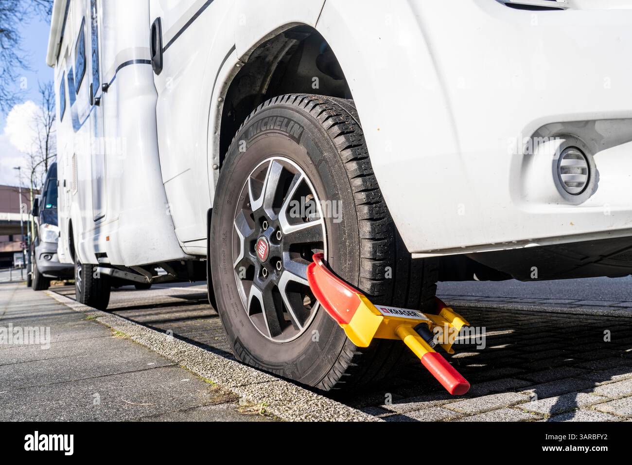 Camper van, parked on the road, secured with a parking clamp, which is supposed to provide additional protection against theft. Stock Photo
