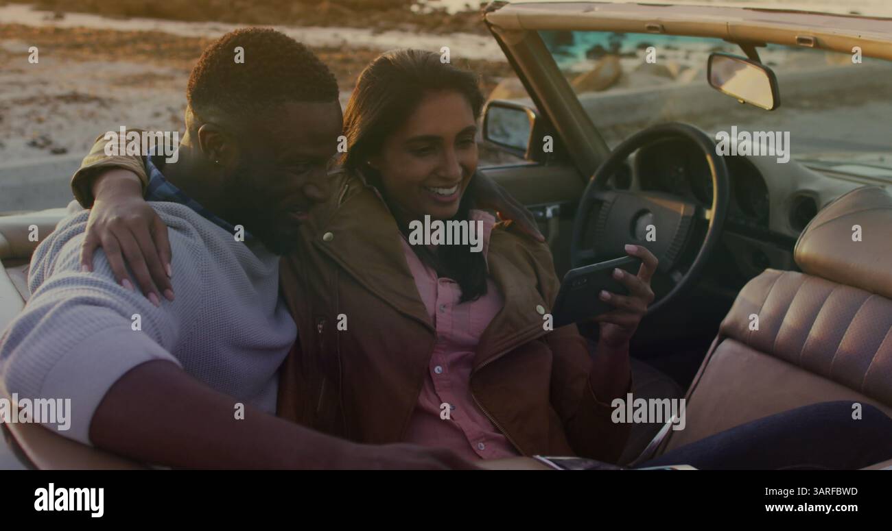 Image of happy diverse couple taking selfie in cabriolet Stock Photo