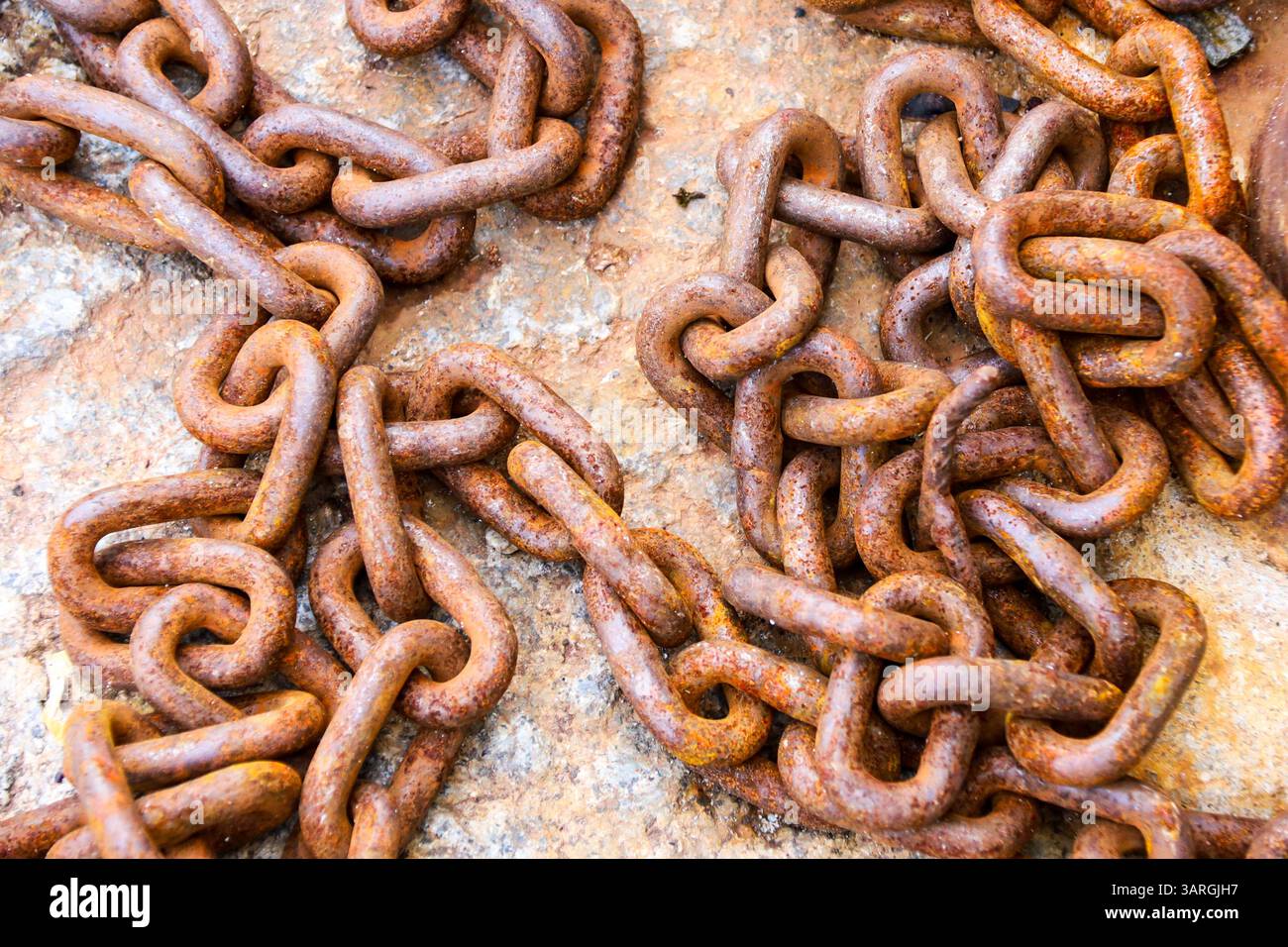 Rusty chains on stone floor on the dock in Spain Stock Photo