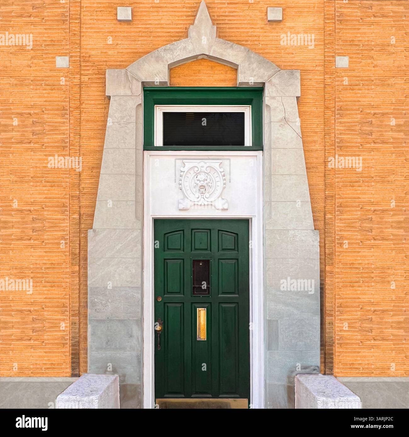 Elegant green door framed by sculpted stone and terra cotta brickwork with a classical crest above the entrance in Chicago. - Smartphone Captured Stock Image