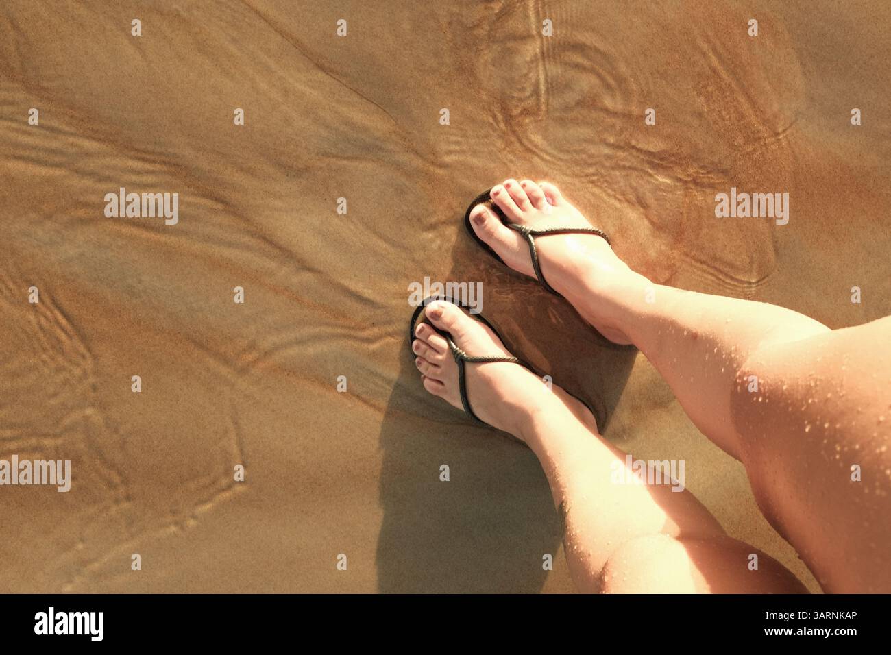 Two feet in flip flops on the sand at a beach in brazil, an example of ...