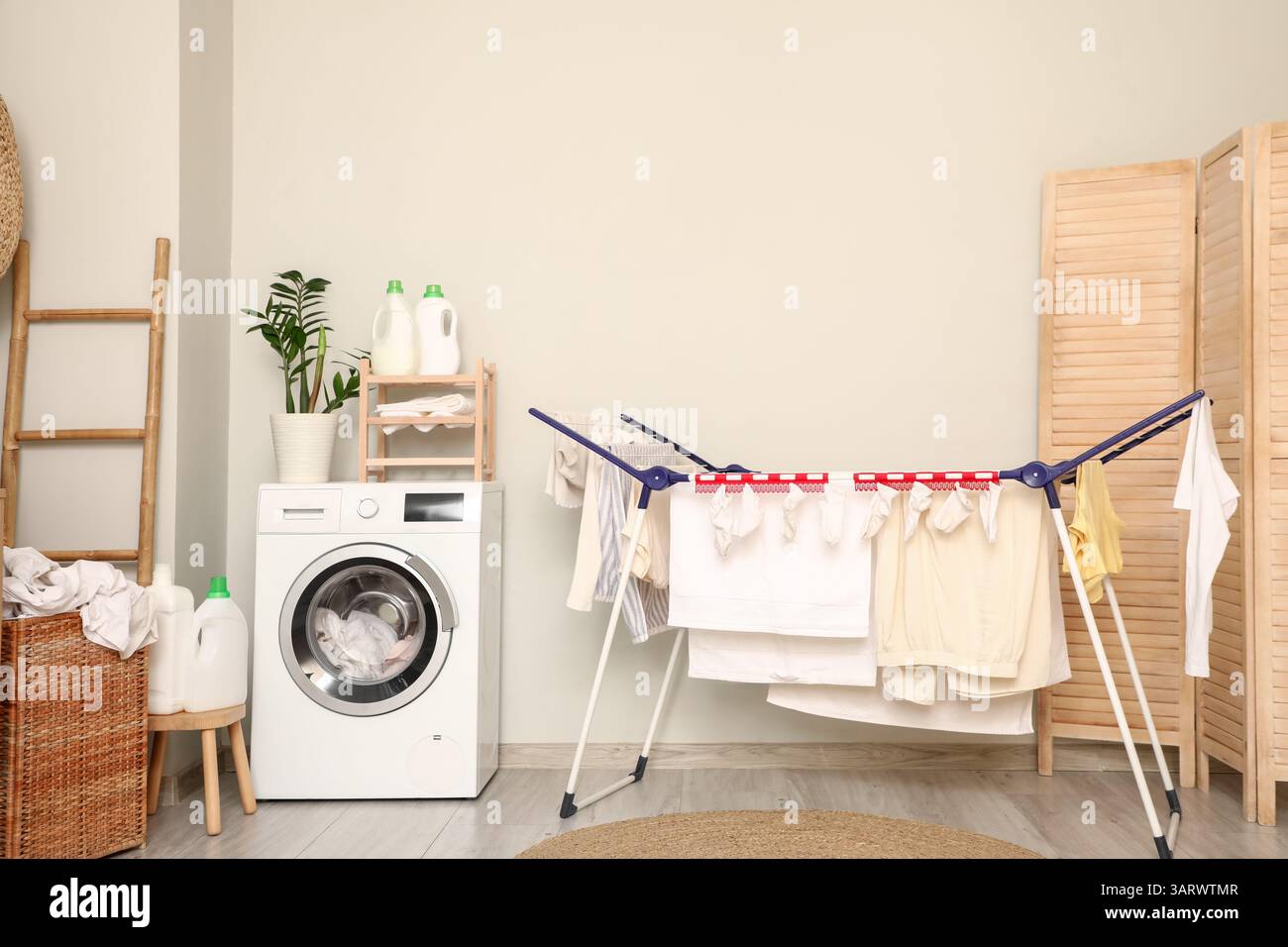 Stylish laundry room with modern washing machine, drying rack and ...