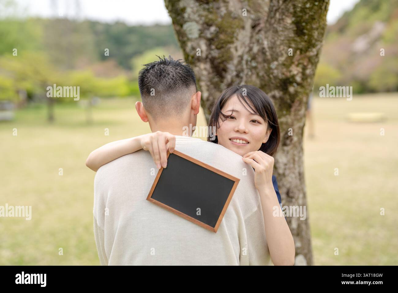 In the spring scene in May, there is an unmanned park, Aichi prefecture. Japanese couples in their early 20s spend time together. They embrace each ot Stock Photo