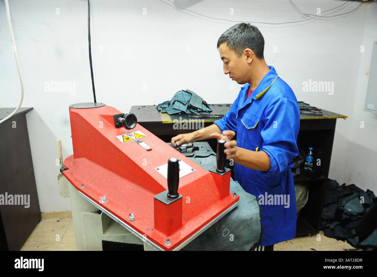 A worker repairs an embroidery machine in a sewing workshop Stock Photo