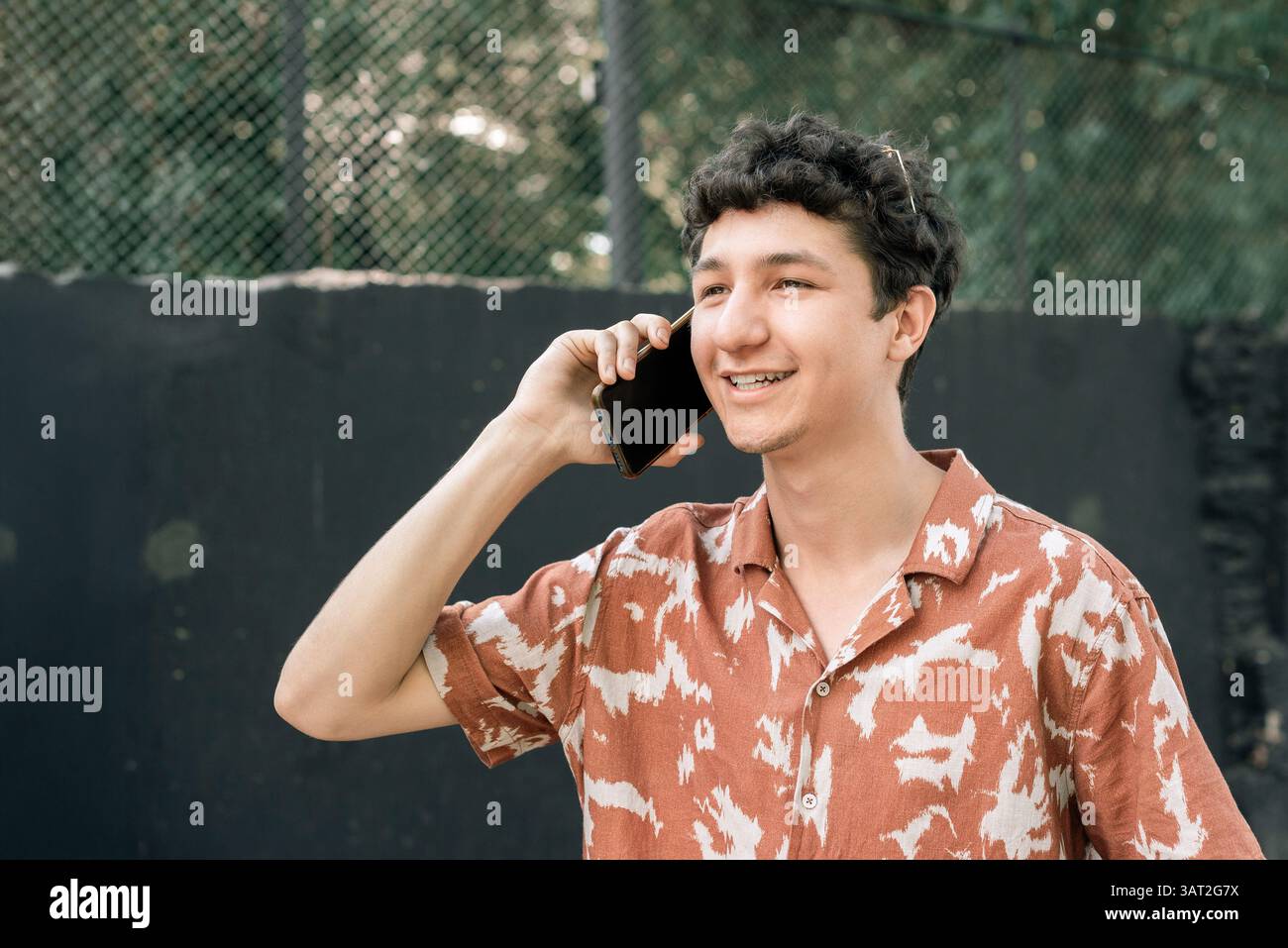 Smiling young man talking on phone outdoors Stock Photo