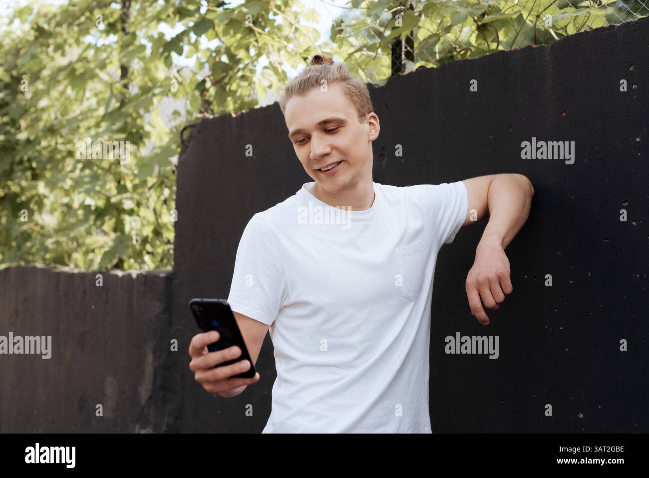 Smiling young man using smartphone outdoors Stock Photo