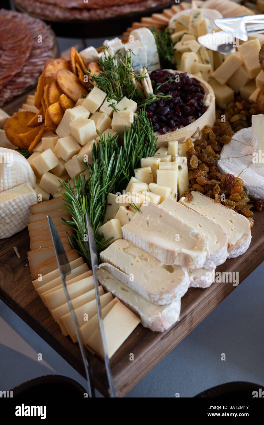 Gourmet Cheese Board with Crackers, Dried Fruits, and Fresh Herb Stock Photo