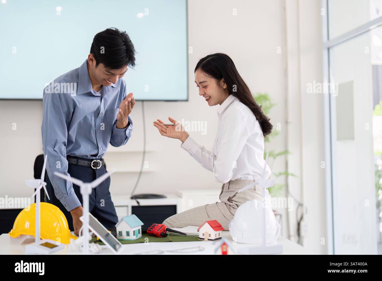 Collaboration and Engineering. Two engineers discussing sustainable construction innovations with scale models. Stock Photo