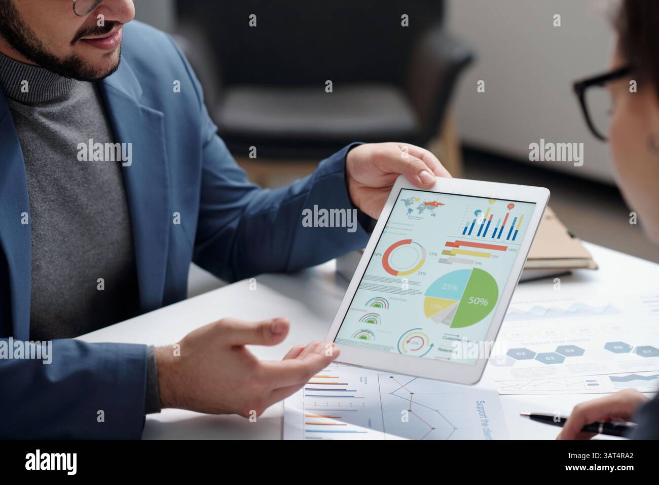 Man Holding Tablet Presenting Data During Meeting Stock Photo