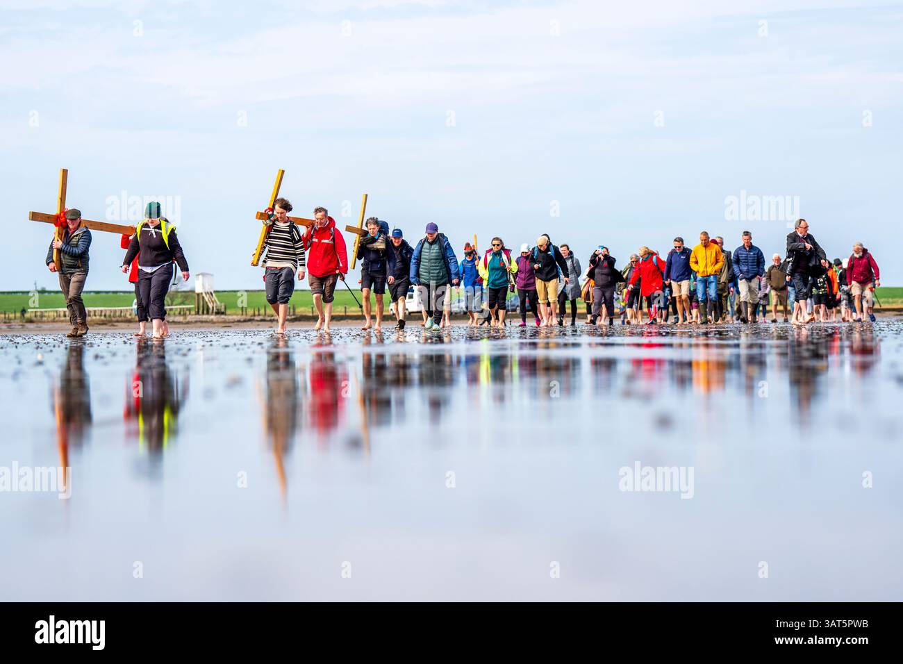 pilgrims-carrying-wooden-crosses-cross-the-sands-at-low-tide-to-the