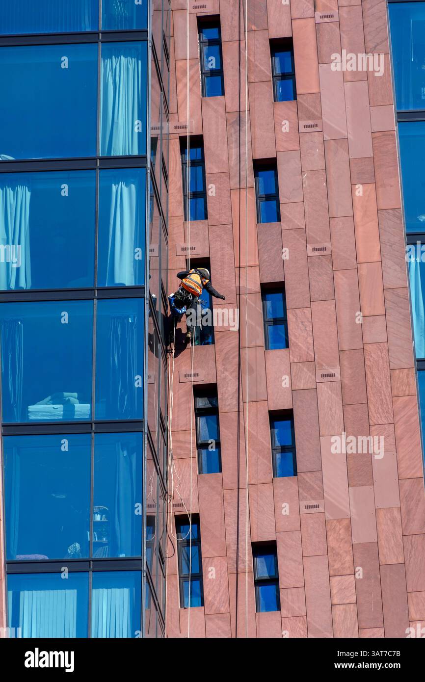 A rope access worker on the Islington Wharf apartment block, Ancoats, Manchester, England, UK Stock Photo