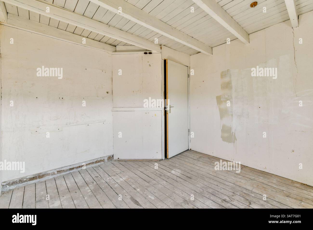 A vacant interior space featuring wooden flooring, white walls, and a ...