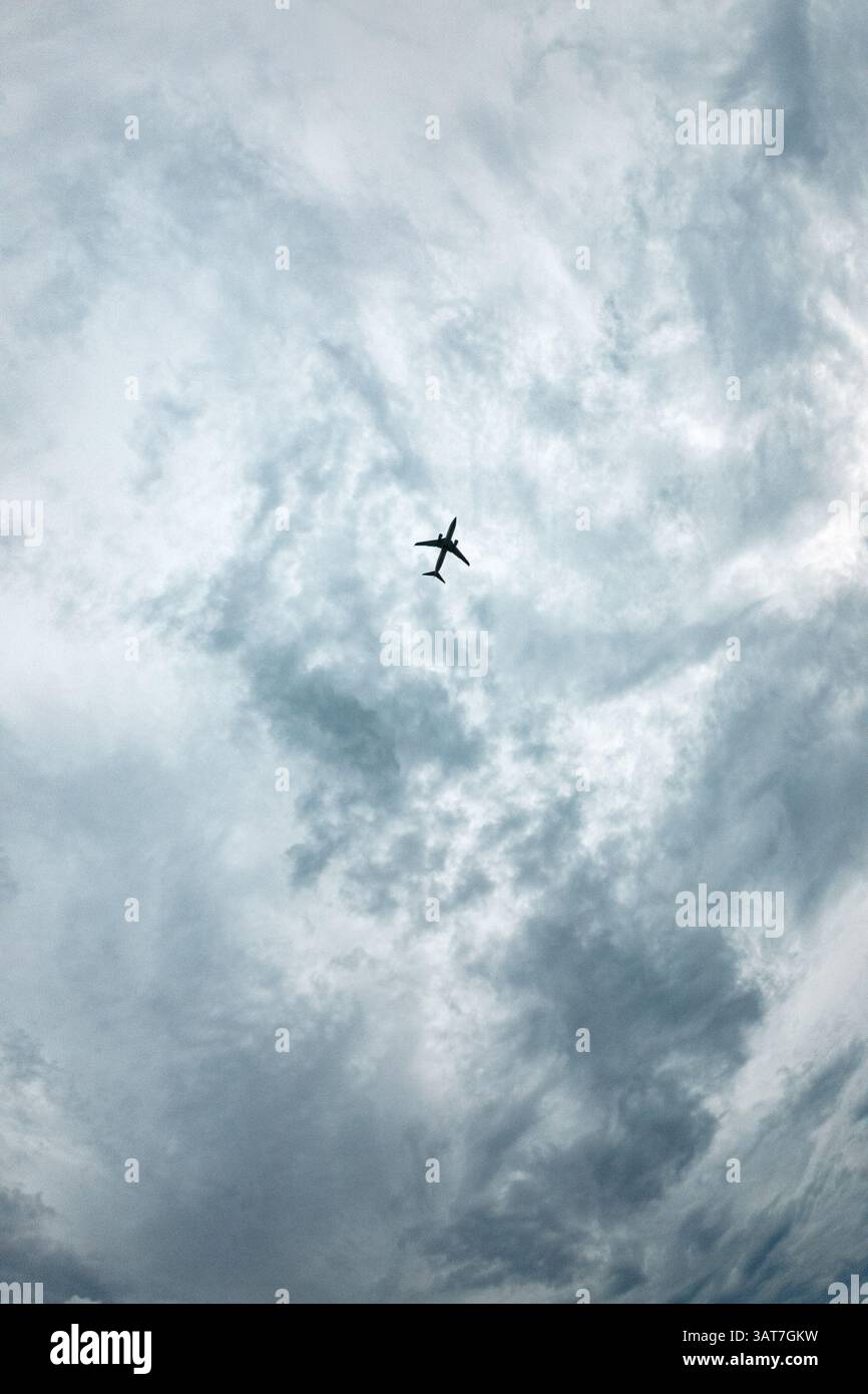 A plane is flying through a cloudy sky. The sky is mostly cloudy with ...