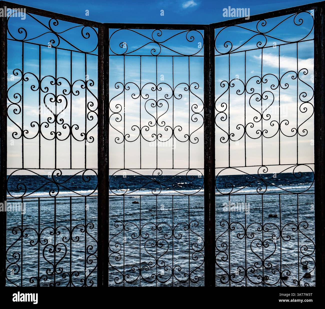 A decorative wrought iron gate with intricate patterns, framing a view ...