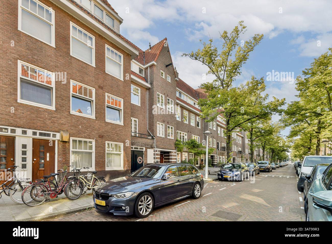 A picturesque urban street lined with trees and parked cars, showcasing ...