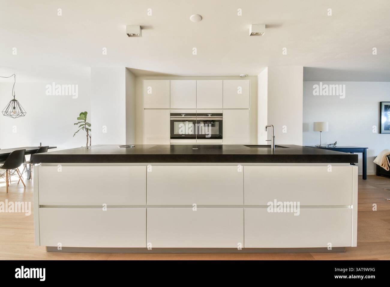 A sleek and contemporary kitchen featuring a large island with a dark ...