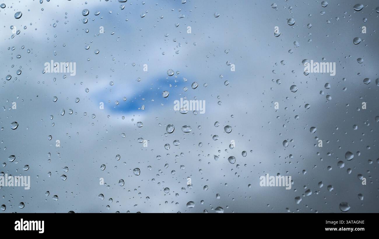 Raindrops on a window with clouds on the background Stock Photo