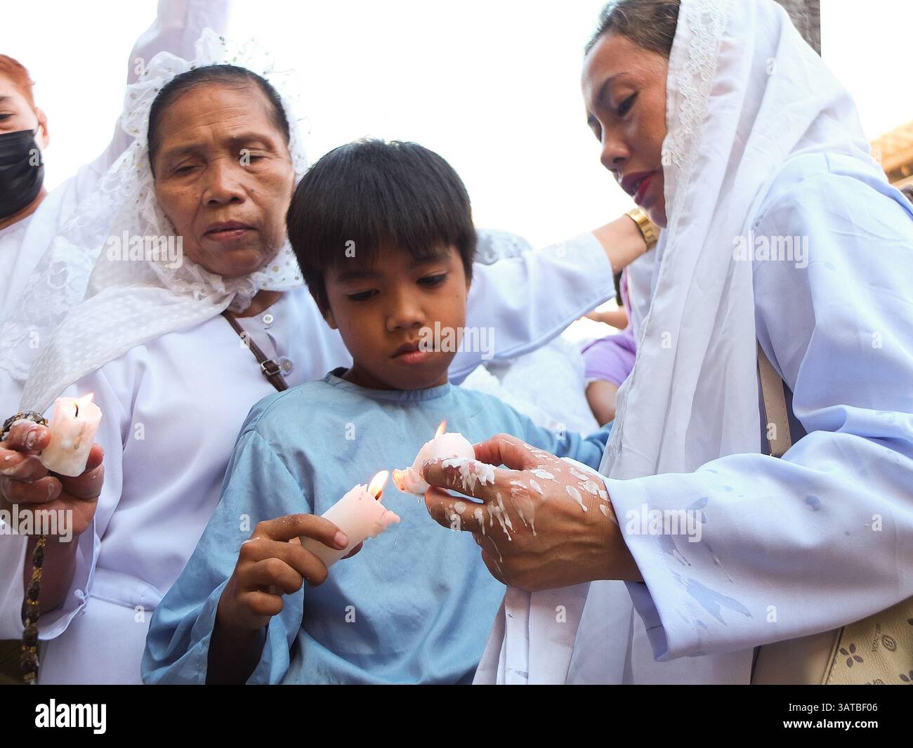 A young boy lights a candle with his grandmother during their act of ...