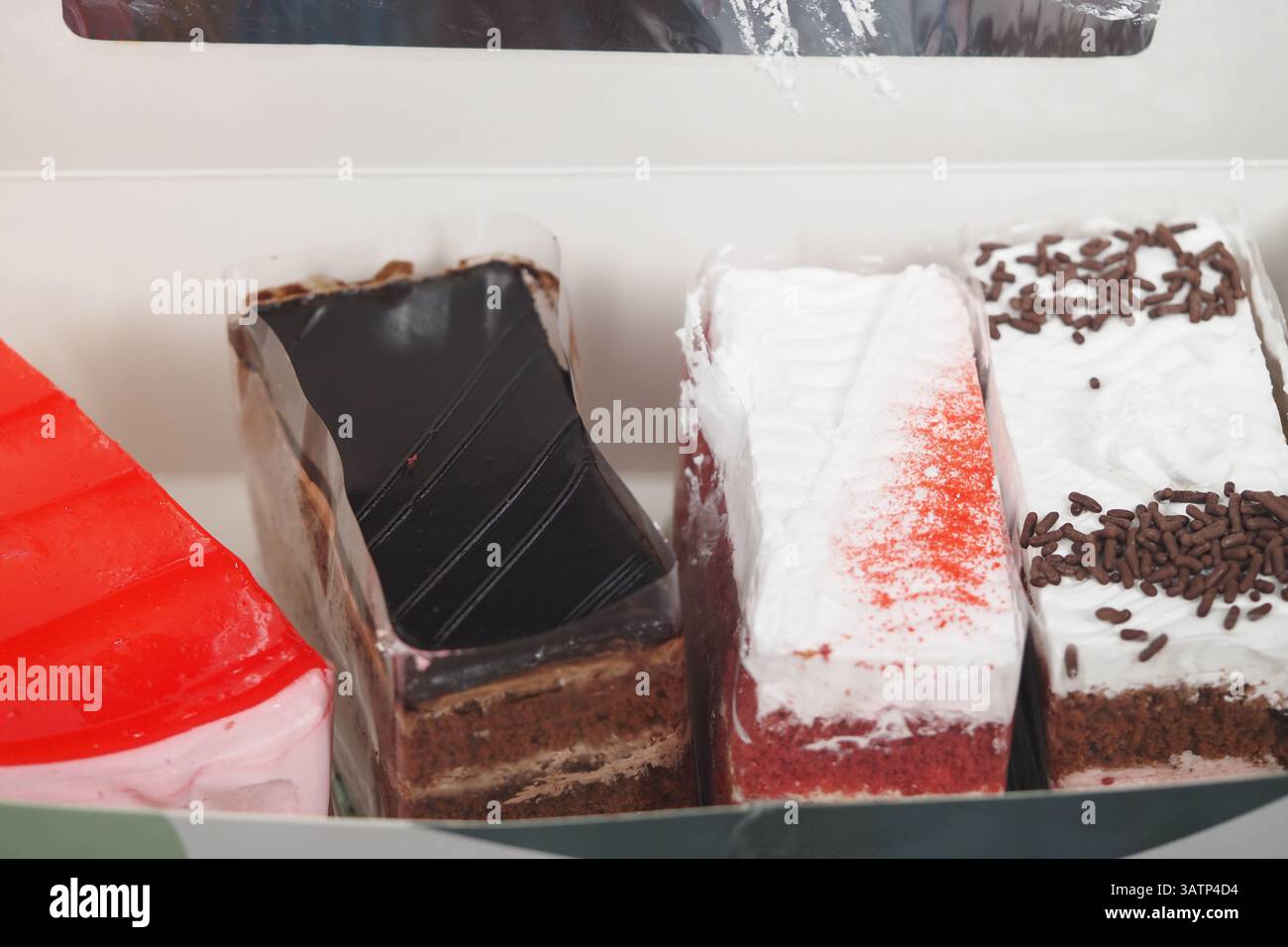 Assorted slices of colorful cakes displayed in a box Stock Photo - Alamy