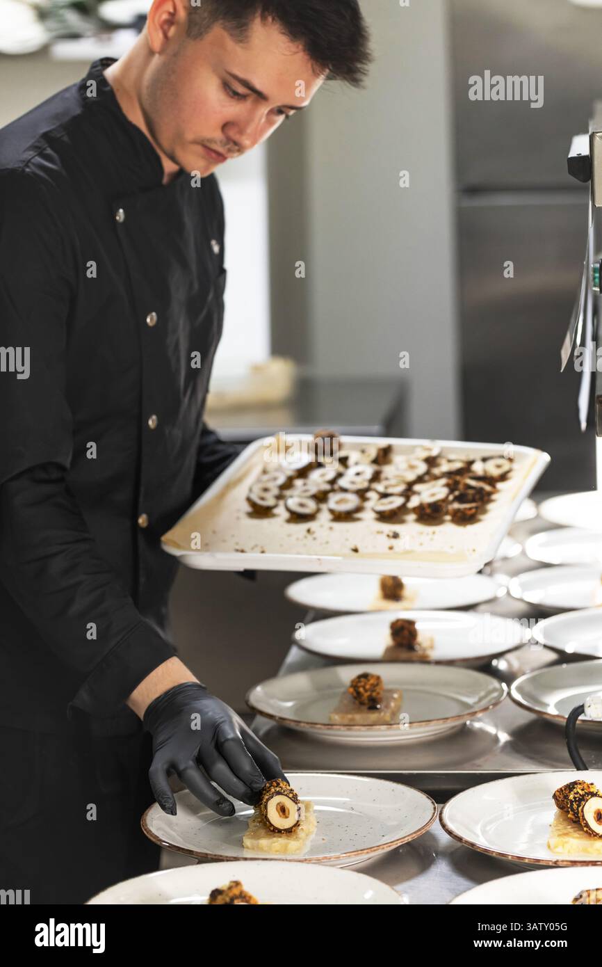 Chef preparing fine dining food table for a party on a professional restaurant kitchen. Stock Photo