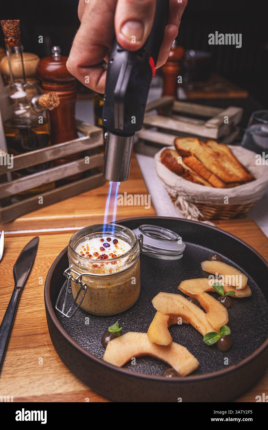 Chef caramelizing creme brulee with a kitchen torch, adding a crispy ...