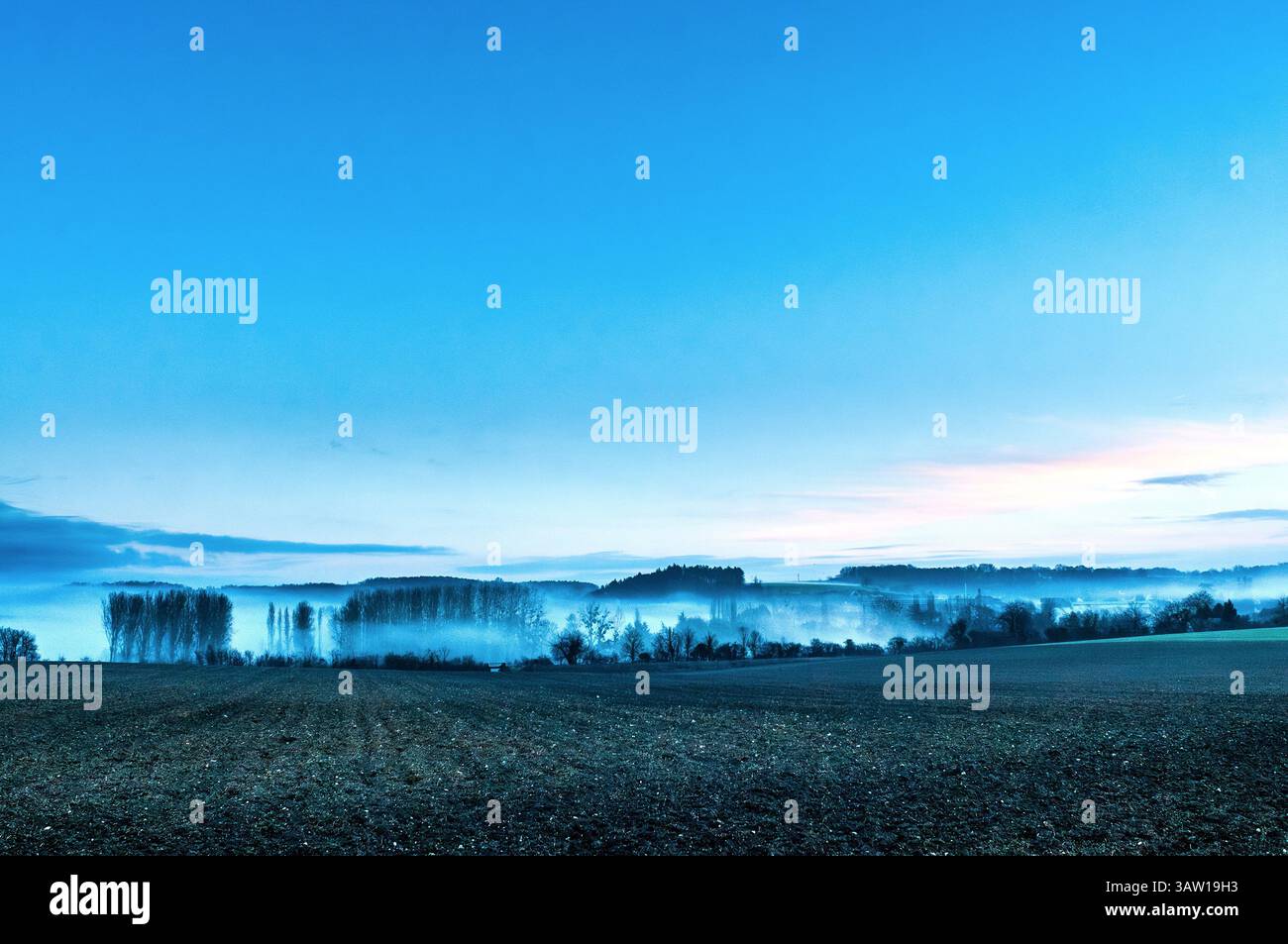 Early morning mist hanging in valley of sud-Touraine farming landscape - central France. Stock Photo
