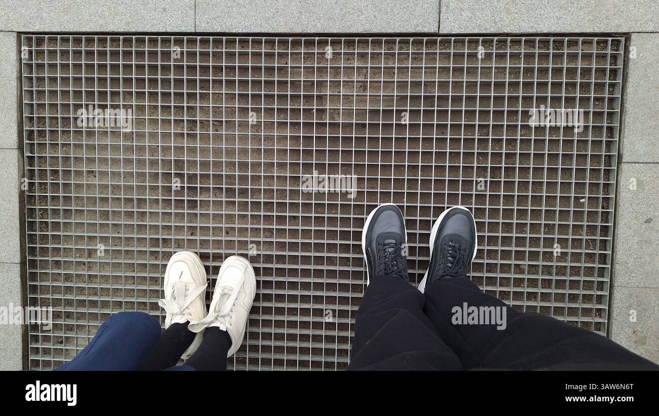 Two pairs of shoes of child and adult on metal grate Stock Photo