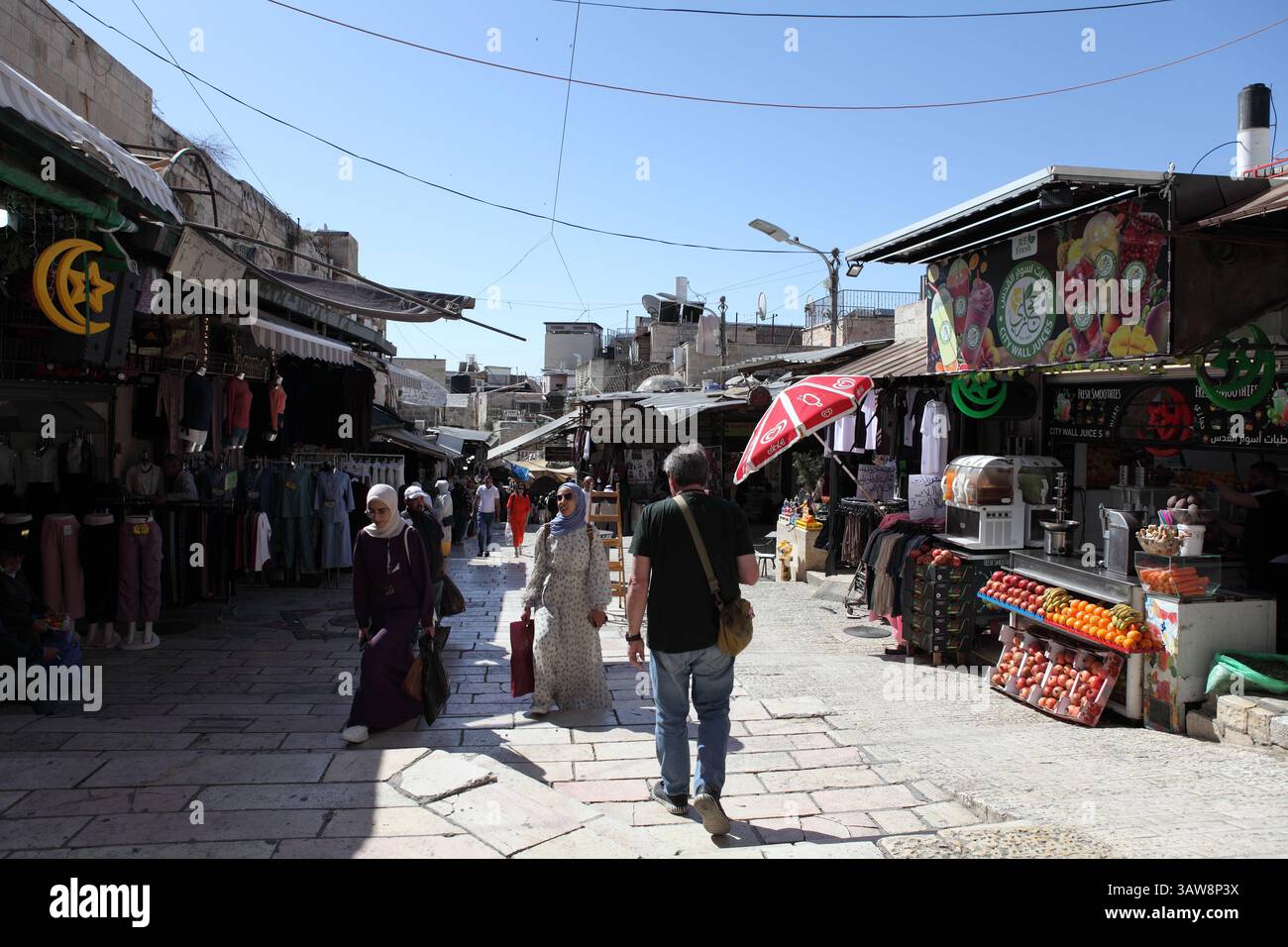 Market stalls & people walk on Rehov Hagay starting at Damascus Gate & heads into Jerusalem Old City in front of Damascus Gate, one of eight gates. Stock Photo