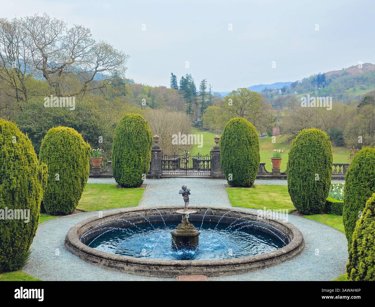 Well-kept symmetrical garden with a round water fountain and trimmed ...