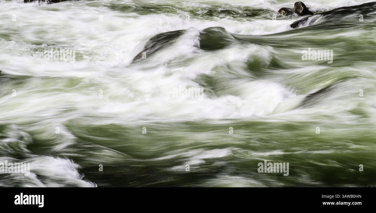 River rages in whitewater shapes in long exposure with green waves ...