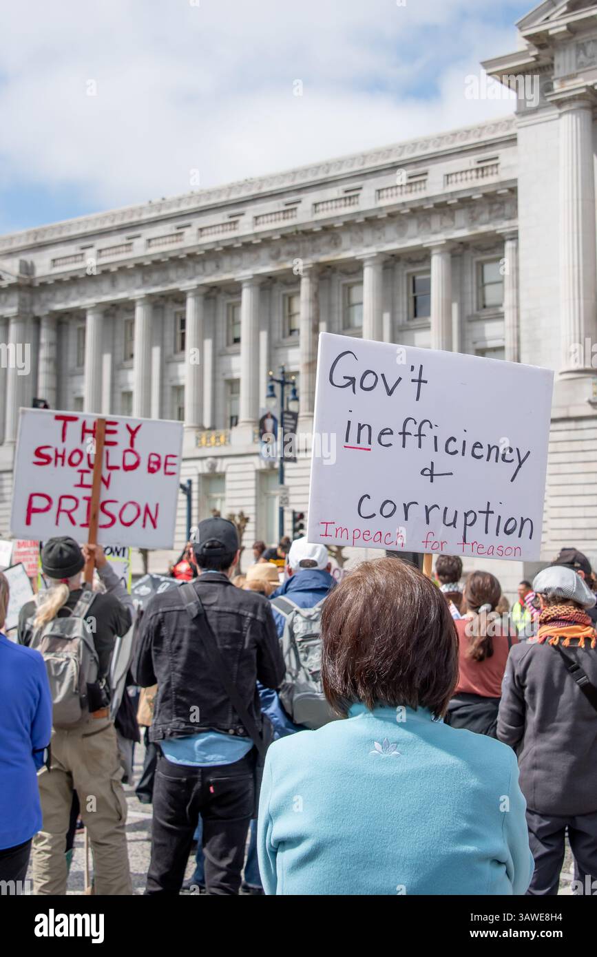 San Francisco, USA. 19th Apr 2025. At Civic Center Plaza. Protesters stand in front of City Hall at the 'Stop the Billionaire Agenda' protest against the Trump Administration. Above the crowd, signs read, 'They should be in prison,' and 'Government inefficiency and corruption. Impeach for treason.'  Credit: Shelly Rivoli/Alamy Live News - Stock Image