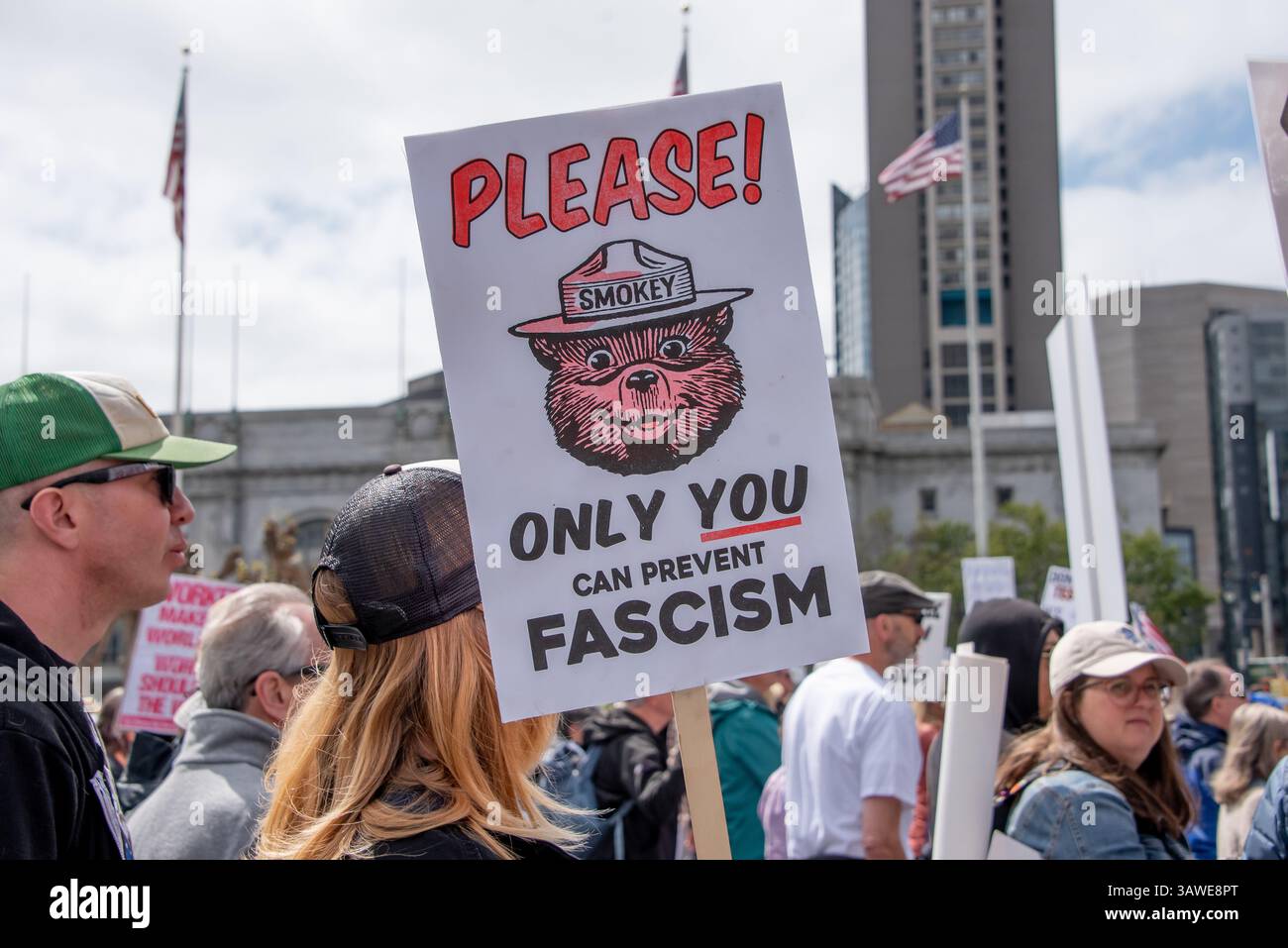 San Francisco, USA. 19th Apr 2025. At Civic Center Plaza during the “Stop the Billionaire Agenda” protest against the Trump Administration, a protester holds a sign with a picture of Smokey Bear reading, 'Please! Only you can prevent fascism.' Credit: Shelly Rivoli/Alamy Live News - Stock Image