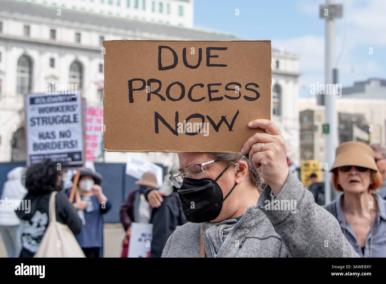 San Francisco, USA. 19th Apr 2025. At Civic Center Plaza. Protesters gather to express many concerns at the “Stop the Billionaire Agenda” protest against the Trump Administration. A woman wearing a mask holds a sign reading, 'Due Process Now.' Credit: Shelly Rivoli/Alamy Live News - Stock Image