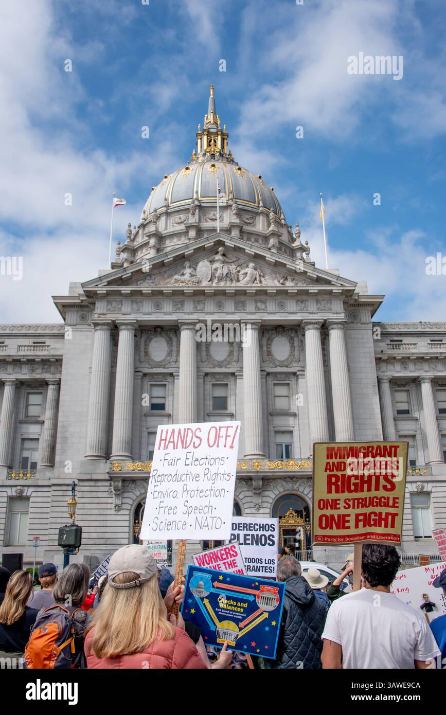 San Francisco, USA. 19th Apr 2025. At Civic Center Plaza, protesters gather in front of San Francisco City Hall to address many different concerns at the “Stop the Billionaire Agenda” protest against the Trump Administration. Some protest signs read, 'Hands off! Fair Elections, Reproductive Rights, Enviro(nmental) Protection, Free Speech, Science, NATO,' while another shows the balance of power defined by the U.S. Constitution with checks and balances.   Credit: Shelly Rivoli/Alamy Live News - Stock Image
