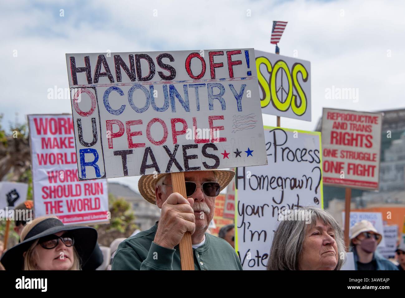 San Francisco, USA. 19th Apr 2025. An older man protesting at thet Civic Center Plaza “Stop the Billionaire Agenda” protest against the Trump Administration holds a sign reading, 'Hands off! Our country, our people, our taxes.'. Credit: Shelly Rivoli/Alamy Live News - Stock Image