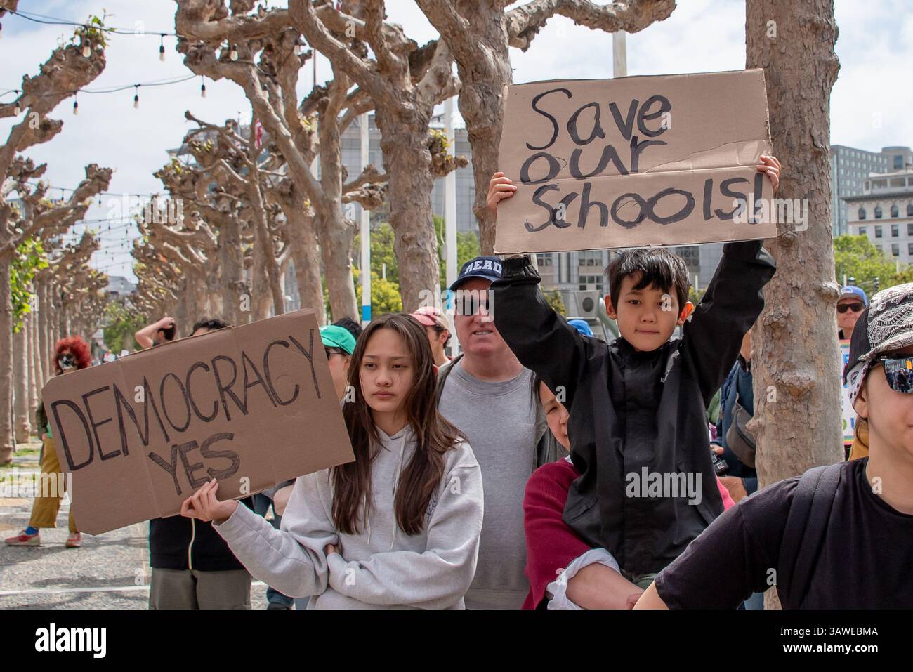 San Francisco, USA. 19th Apr 2025. At the Civic Center Plaza “Stop the Billionaire Agenda” protest against the Trump Administration, a young boy holds a sign reading, 'Save our schools!' while a young woman next to him holds a sign reading, 'Democracy Yes.' Credit: Shelly Rivoli/Alamy Live News - Stock Image