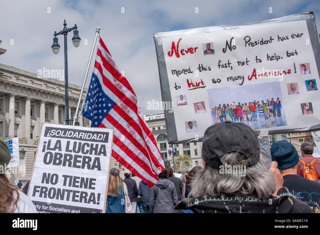San Francisco, USA. 19th Apr 2025. Above the protesters at Civic Center Plaza's “Stop the Billionaire Agenda” protest against the Trump Administration, an upside down American flag is seen beside a sign reading, 'Never. No president has ever moved this fast, not to help, but to hurt so many Americans!.'    Credit: Shelly Rivoli/Alamy Live News - Stock Image