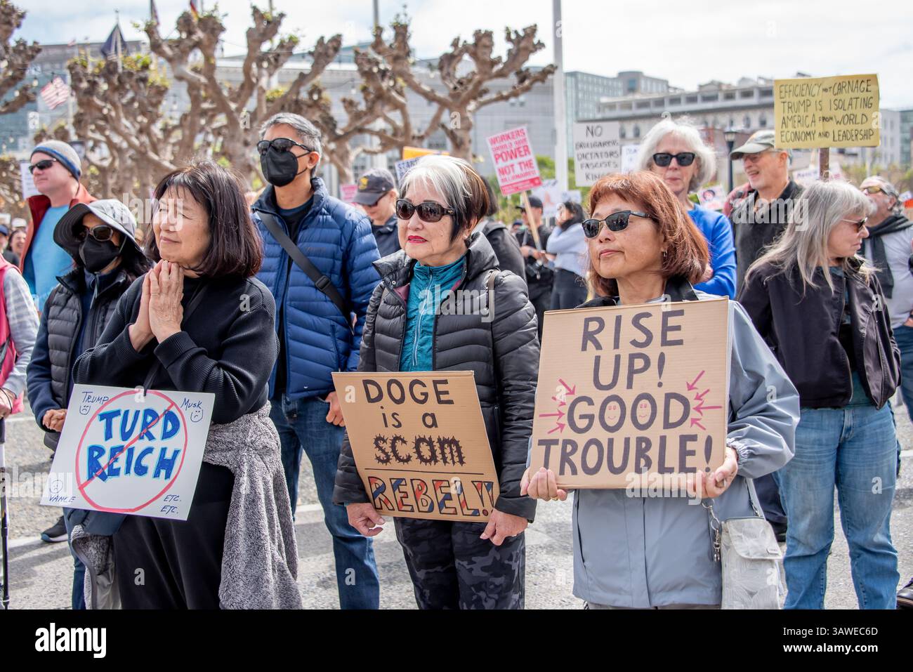 San Francisco, USA. 19th Apr 2025. At Civic Center Plaza, three older women stand together with protest signs reading, 'Turd Reich,' 'DOGE is a scam. Rebel!' and 'Rise up! Good trouble!' during the “Stop the Billionaire Agenda” protest against the Trump Administration. Credit: Shelly Rivoli/Alamy Live News - Stock Image