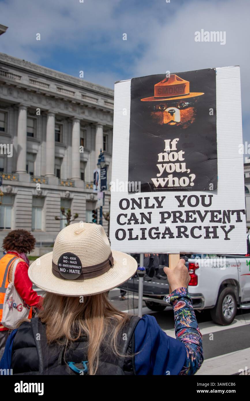 San Francisco, USA. 19th Apr 2025. At Civic Center Plaza, a woman protester arrives with a sign showing a vintage Smokey Bear poster with words reading, 'If not you, who? Only you can prevent oligarchy,' “Stop the Billionaire Agenda” protest against the Trump Administration. Credit: Shelly Rivoli/Alamy Live News - Stock Image