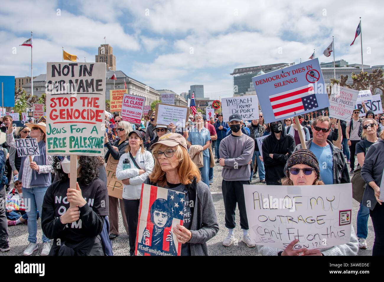 San Francisco, USA. 19th Apr 2025. At Civic Center Plaza's “Stop the Billionaire Agenda” protest against the Trump Administration, numerous protesters listen to speakers while holding signs addressing numerous concerns. Protest signs read, 'Not in our name, Stop the Genocide, Jews for a Free Palestine,' Impeach Trump, Deport Musk,' 'Democracy dies in silence,' and 'All of my outrage can't fit on this sign!?!?!' Credit: Shelly Rivoli/Alamy Live News - Stock Image