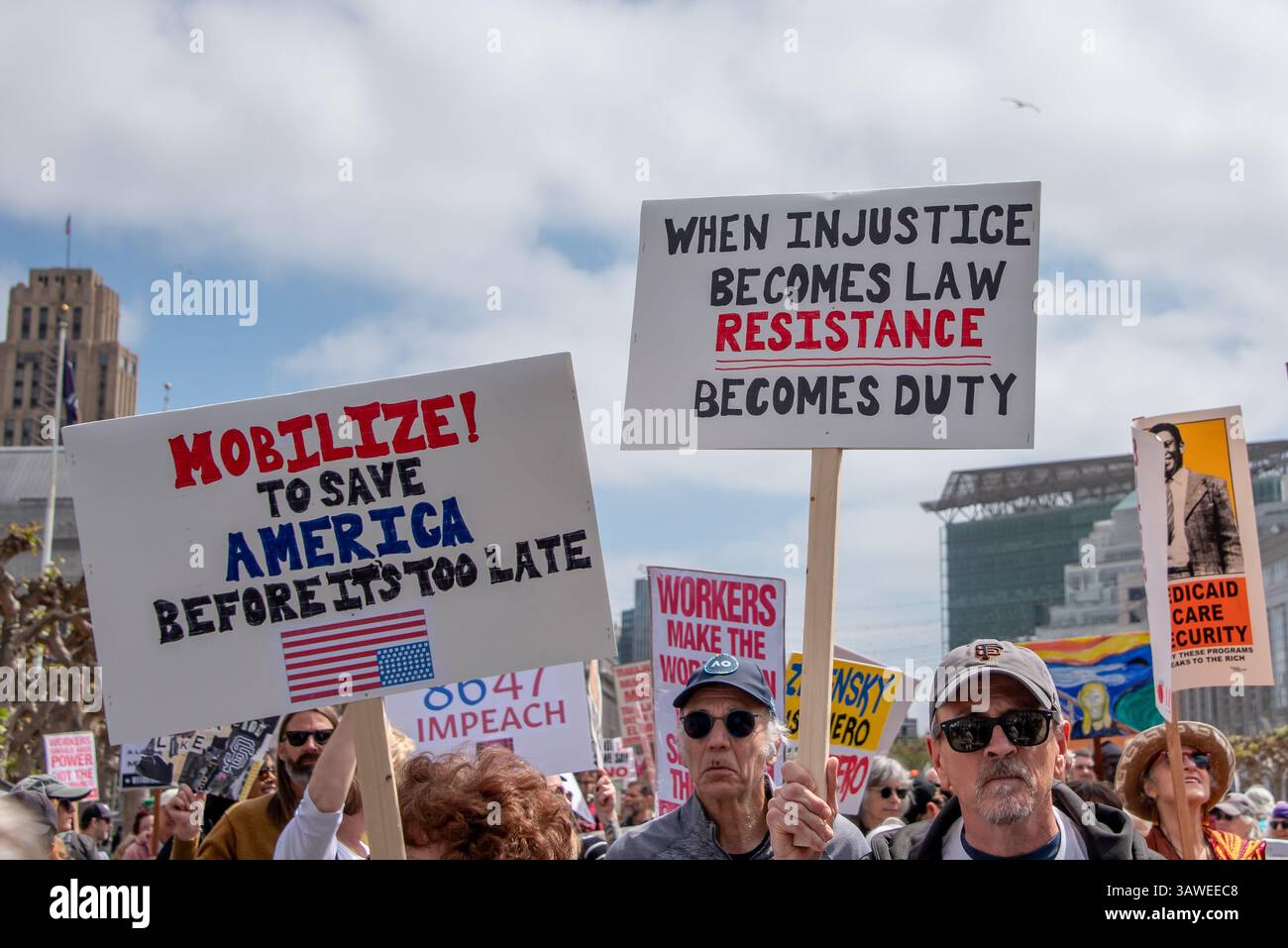 San Francisco, USA. 19th Apr 2025. A crowd of protesters listens to speakers at Civic Center Plaza.during the “Stop the Billionaire Agenda” protest against the Trump Administration. Many signs are seen among the crowd, including, 'Mobilize! To save America before it's too late,' and 'When injustice becomes law, resistance becomes duty.' Credit: Shelly Rivoli/Alamy Live News - Stock Image