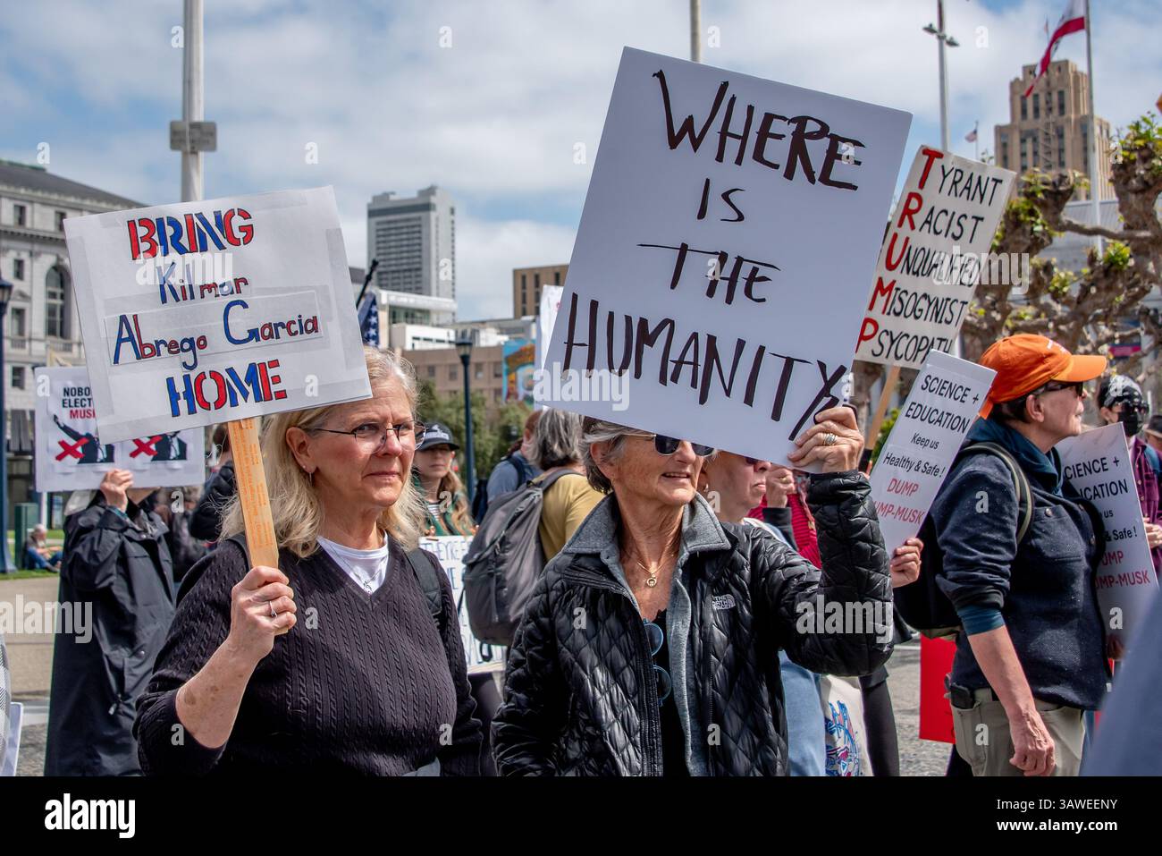 San Francisco, USA. 19th Apr 2025. At the Civic Center Plaza “Stop the Billionaire Agenda” protest against the Trump Administration, two women stand together among the protesters with signs reading, 'Bring Kilmar Abrego Garcia home,' and 'Where is the humanity?'   Credit: Shelly Rivoli/Alamy Live News - Stock Image