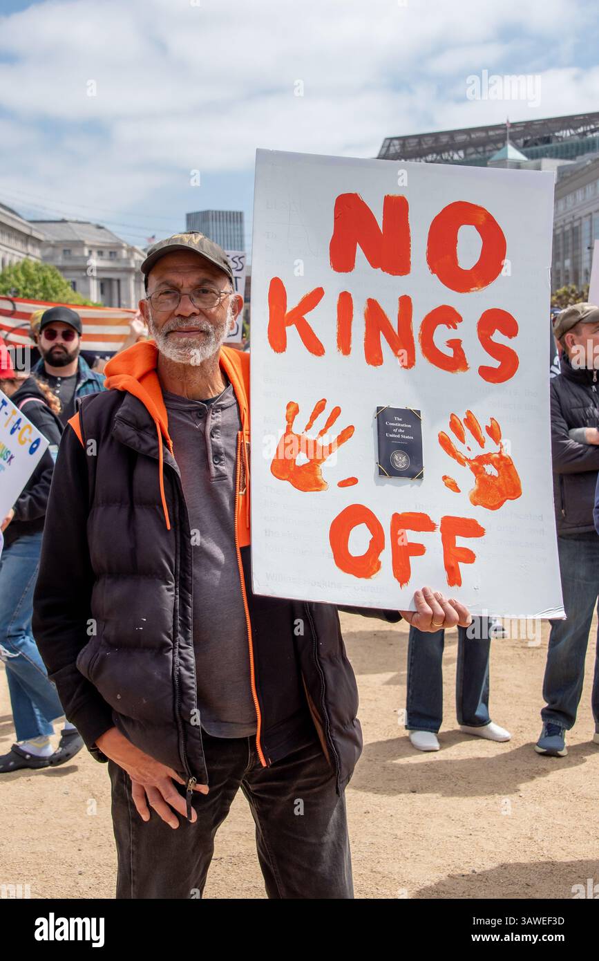 San Francisco, USA. 19th Apr 2025. At the Civic Center Plaza “Stop the Billionaire Agenda” protest against the Trump Administration, a man displays  his sign reading, 'No Kings,' with hand prints and the word 'off' beside a copy of the Constitution of the United States affixed to his sign. Credit: Shelly Rivoli/Alamy Live News - Stock Image