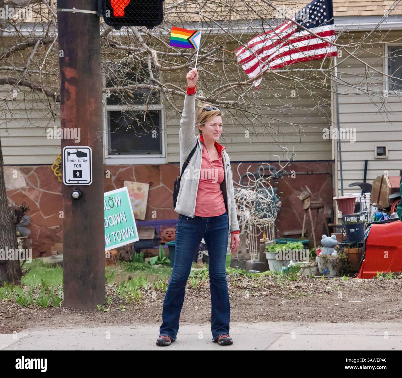 Glenwood Springs, Colorado, USA. 5 April 2025. A woman waves a Progress Pride flag in support of LGBTQ at the Hands Off! protest against Trump. Stock Photo
