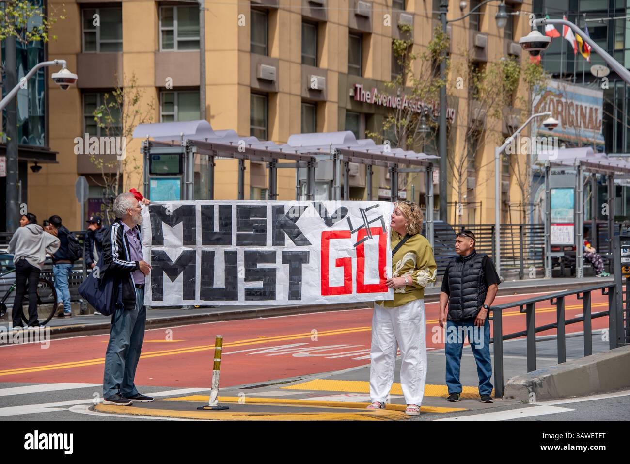 San Francisco, USA. 19th Apr 2025. Two protesters hold a banner reading, 'Musk Must Go,' while standing on the island in Van Ness Avenue across the street from the Tesla showroom and dealership in San Francisco. Credit: Shelly Rivoli/Alamy Live News - Stock Image