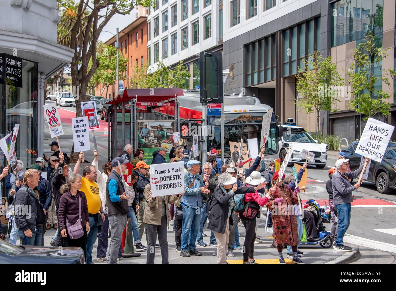 San Francisco, USA. 19th Apr 2025. Protesters gather on the street corner outside the Tesla showroom and dealership in San Francisco. Many drivers honk and cheer as they pass by their signs reading, 'Trump and Musk have got to go,' 'Trump & Musk: The real domestic terrorists,' and 'Hands off our democracy.'   Credit: Shelly Rivoli/Alamy Live News - Stock Image