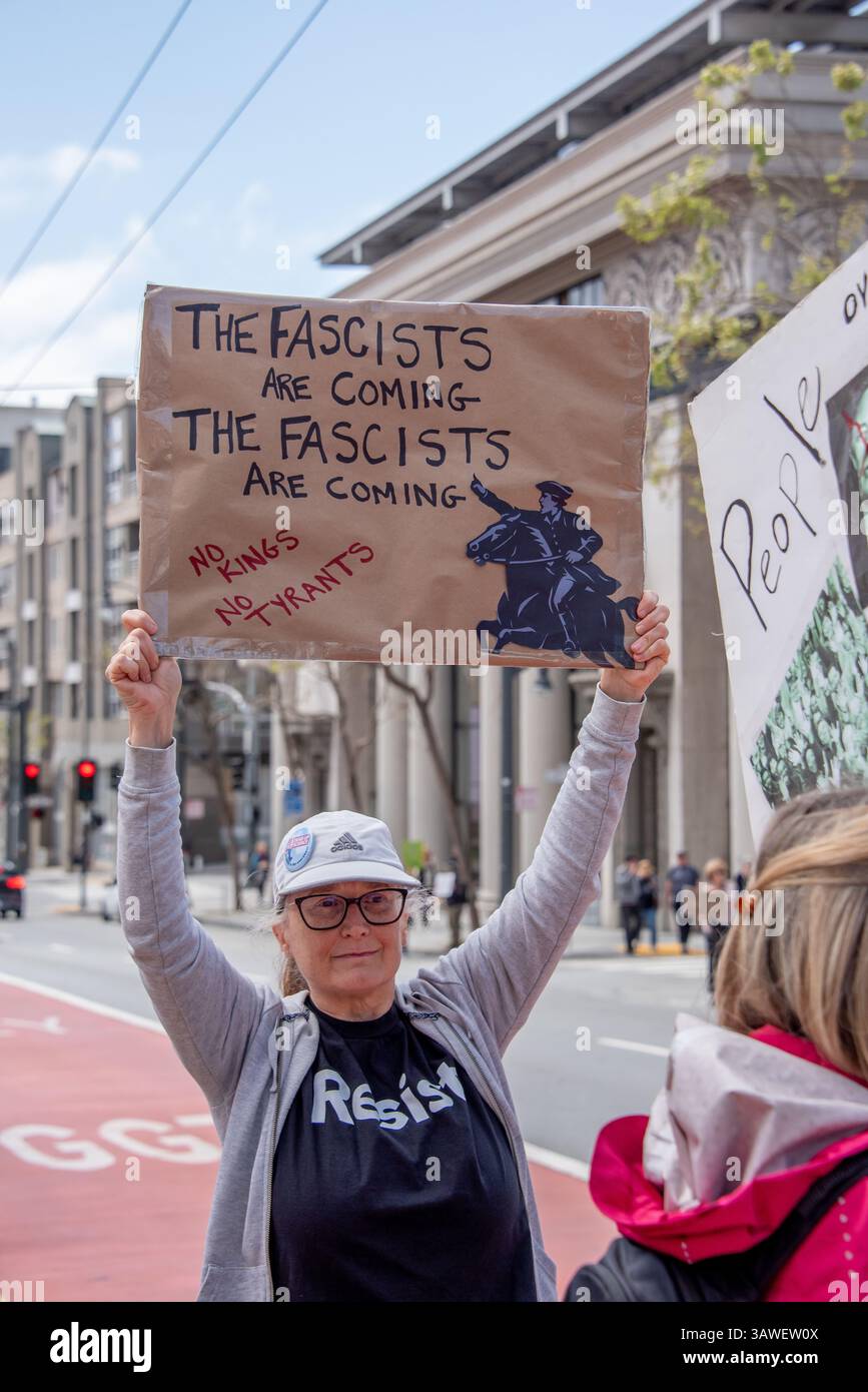 San Francisco, USA. 19th Apr 2025. Protesters gather outside the Tesla showroom and dealership in San Francisco, where one woman holds a sign reading, 'The Fascists are coming, the Fascists are coming. No kings. No Tyrants,' with an illustration on the sign that appears to reference Paul Revere as history marks the 250th anniversary of his famous ride.  Credit: Shelly Rivoli/Alamy Live News - Stock Image